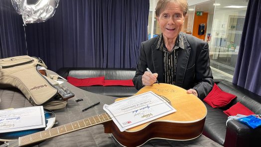 Sir Cliff Richard signing the two Vintage Acoustic Guitar Aid V300 guitars auctioning 3rd September