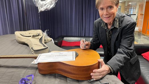 Sir Cliff Richard signing the two Vintage Acoustic Guitar Aid V300 guitars auctioning 3rd September