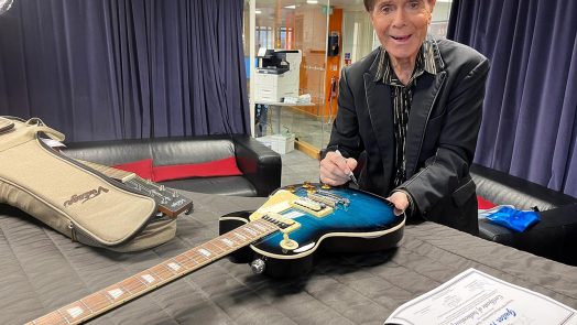 Sir Cliff Richard signing the two Vintage Guitar Aid V100 guitars