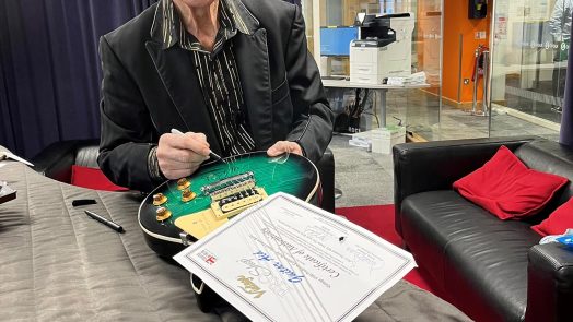 Sir Cliff Richard signing the two Vintage Guitar Aid V100 guitars